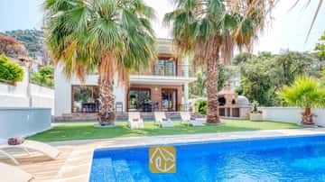 Privater Pool mit blauen Mosaikfliesen und Sonnenliegen auf dem Rasen der Villa Marcella, umgeben von Palmen und mit einem gemauerten Grill ausgestattet.