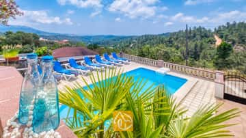 Privater Außenpool in der Villa Santa Maria mit blauen Liegen auf der gefliesten Terrasse und Blick auf die grünen Hügel in der Ferne