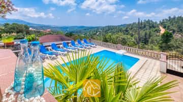 Privater Außenpool in der Villa Santa Maria mit blauen Liegen auf der gefliesten Terrasse und Blick auf die grünen Hügel in der Ferne