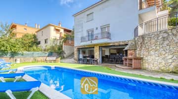 Privater Pool mit blauen Sonnenliegen und Steinterrasse in der Villa Nicky, die durch eine weiße mehrstöckige Außenfassade, einen Außengrill und einen offenen Terrassen-Essbereich besticht.