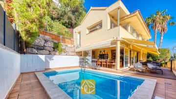 Privater Pool in der Villa Santa Cristina mit gefliester Terrasse, gelben Markisen und Sonnenliegen auf einem Holzdeck direkt an der gelben Außenfassade.