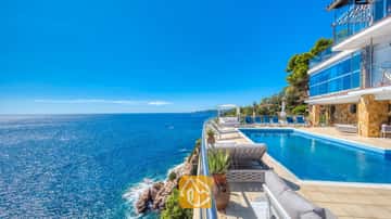 Klippen-Infinity-Pool in der Villa Infinity mit blauen Liegen und weitem Meerblick unter einem blauen Himmel