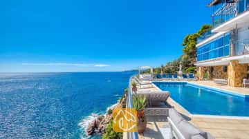 Klippen-Infinity-Pool in der Villa Infinity mit blauen Liegen und weitem Meerblick unter einem blauen Himmel