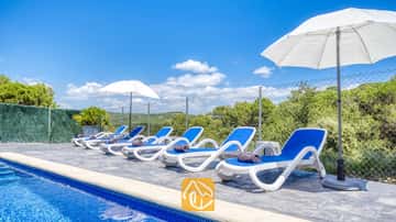 Weiße und blaue Sonnenliegen reihen sich am Pool der Villa Fransisca auf, begleitet von weißen Sonnenschirmen vor einem blauen Himmel.