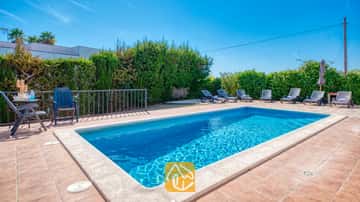 Privater Pool mit klarem blauen Wasser und umlaufenden Sonnenliegen auf einer gepflasterten Terrasse der Villa Yara in Spanien.