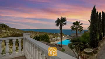 Terrasse mit Blick auf die Villa Tropicana, privatem Swimmingpool, Palmen und Meerblick unter einem rosa- und blauen Abendhimmel.