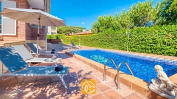 Privater Außenpool der Villa Beyonce mit blauem Wasser, Metallhandläufen und einer Steinernen Statue neben einer Reihe grauer Sonnenliegen auf einer gefliesten Terrasse.