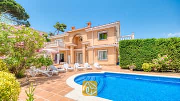 Privater Swimmingpool und Terrasse der Villa Primavera mit weißen Sonnenliegen, Terrakottafliesen und einer zweistöckigen, pfirsichfarbenen Fassade unter blauen Himmel.