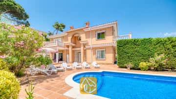 Privater Swimmingpool und Terrasse der Villa Primavera mit weißen Sonnenliegen, Terrakottafliesen und einer zweistöckigen, pfirsichfarbenen Fassade unter blauen Himmel.