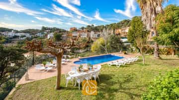 Privater Pool in der Villa Marysol, umgeben von einer gefliesten Terrasse, einer Rasenfläche, einem Esstisch mit Stühlen und Sonnenliegen vor einer malerischen Hangkulisse