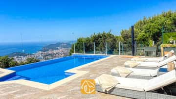 Privater Infinity-Pool und Steinterrasse der Villa VistaMar mit weißen Sonnenliegen, gefalteten Decken und einem weiten Blick auf die Küste.